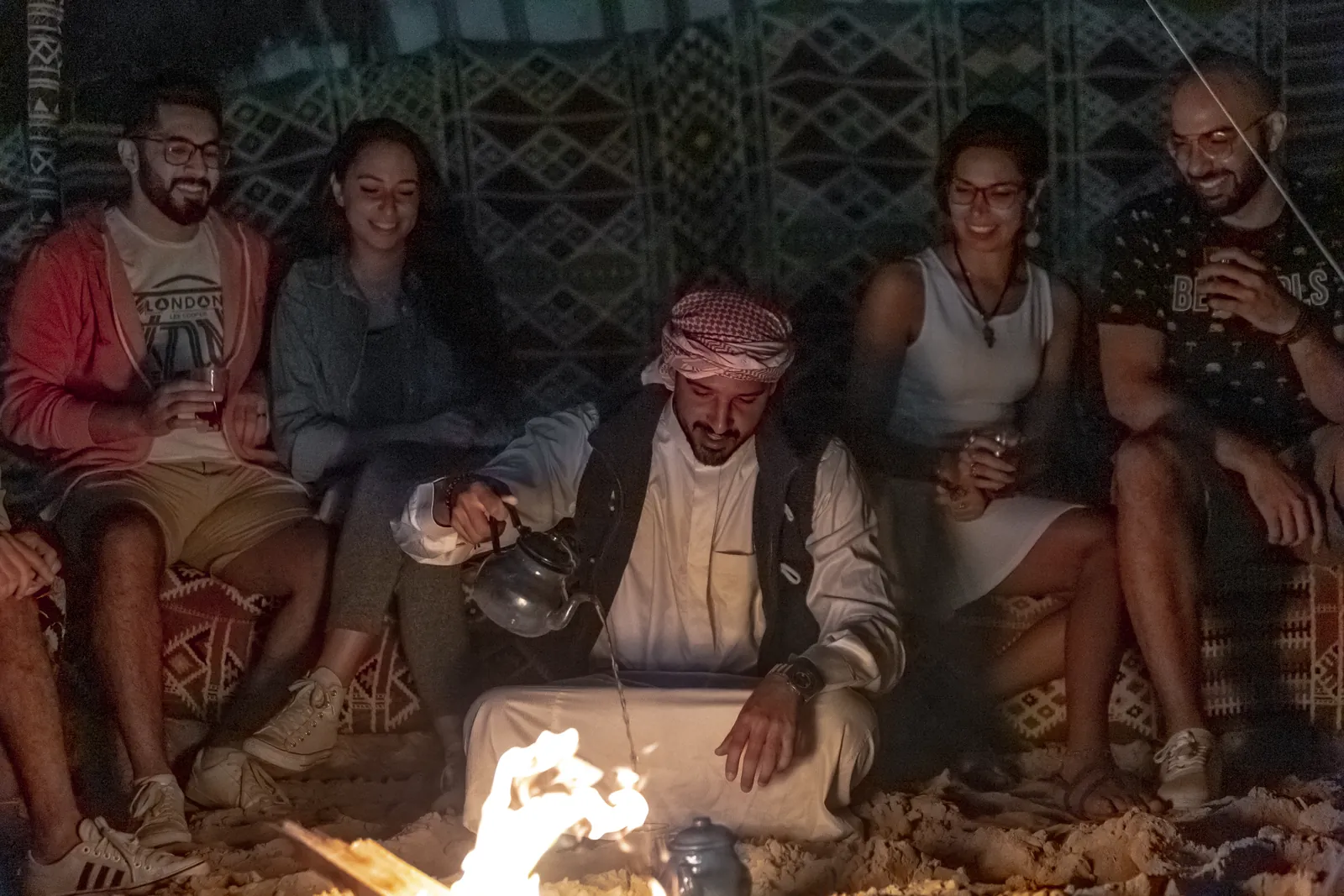 Friends laughing around a fire pit at night