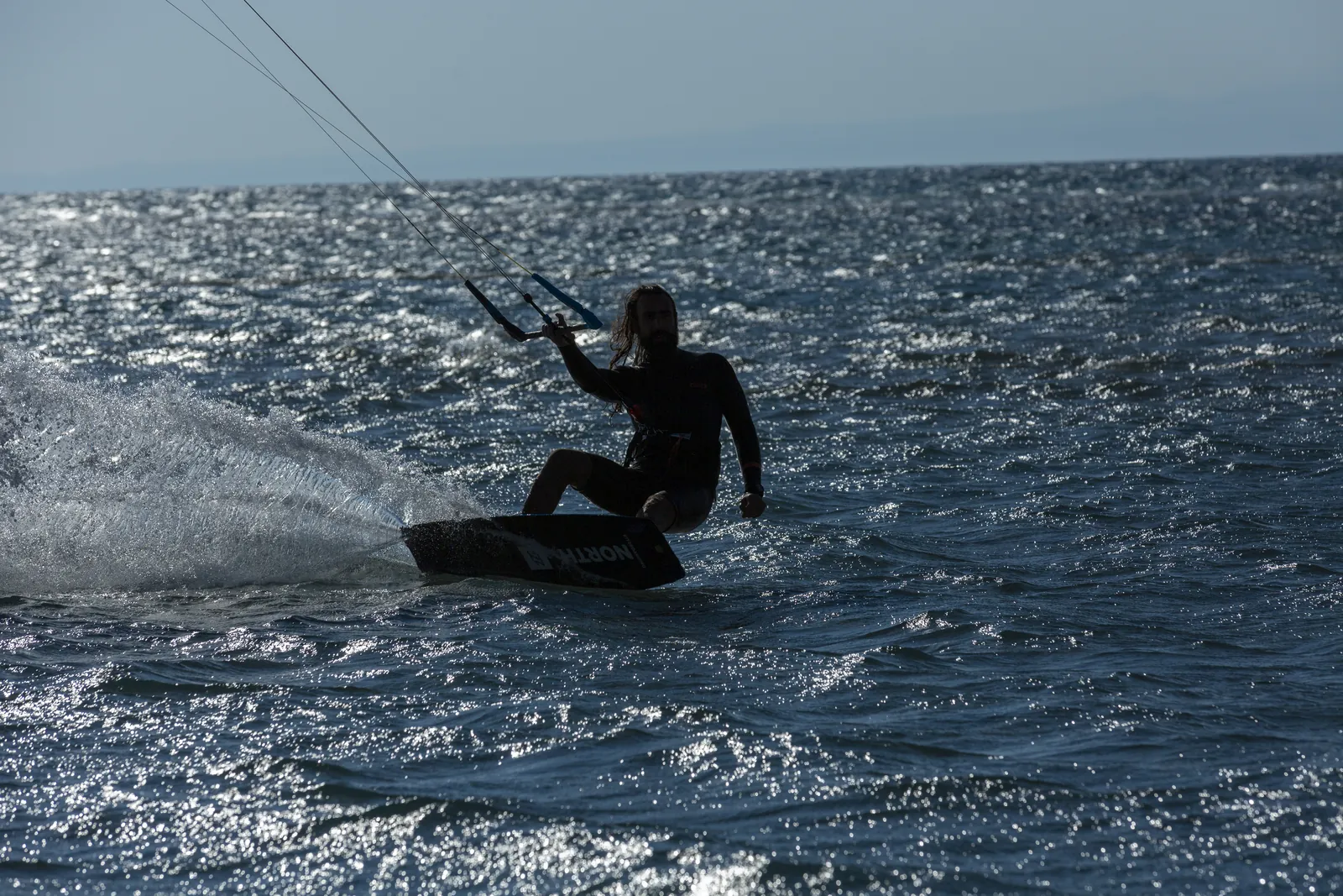 Kitesurfer carving spray off a turn