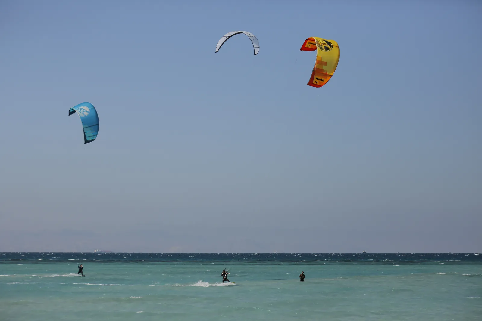 Kites filling the sky over turquoise water in Ras Sudr